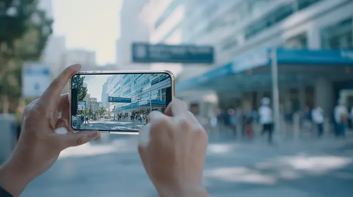 Person using a smartphone to view augmented reality directions outside a hospital — showing how AR solves real-world navigation tasks without extra gear.